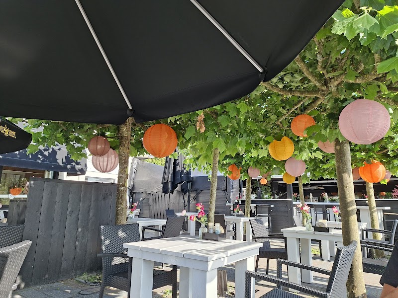 Sunlit garden terrace with lanterns and white tables at Restaurant De Gezelligheid