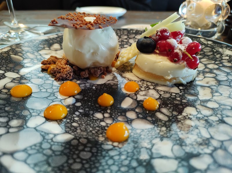 An elegant plated dessert with berries and citrus dots