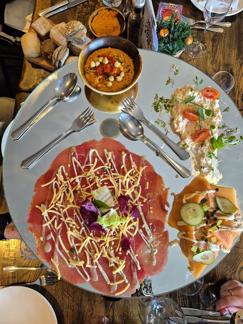 Overhead view of a sharing platter with carpaccio, salmon and dips